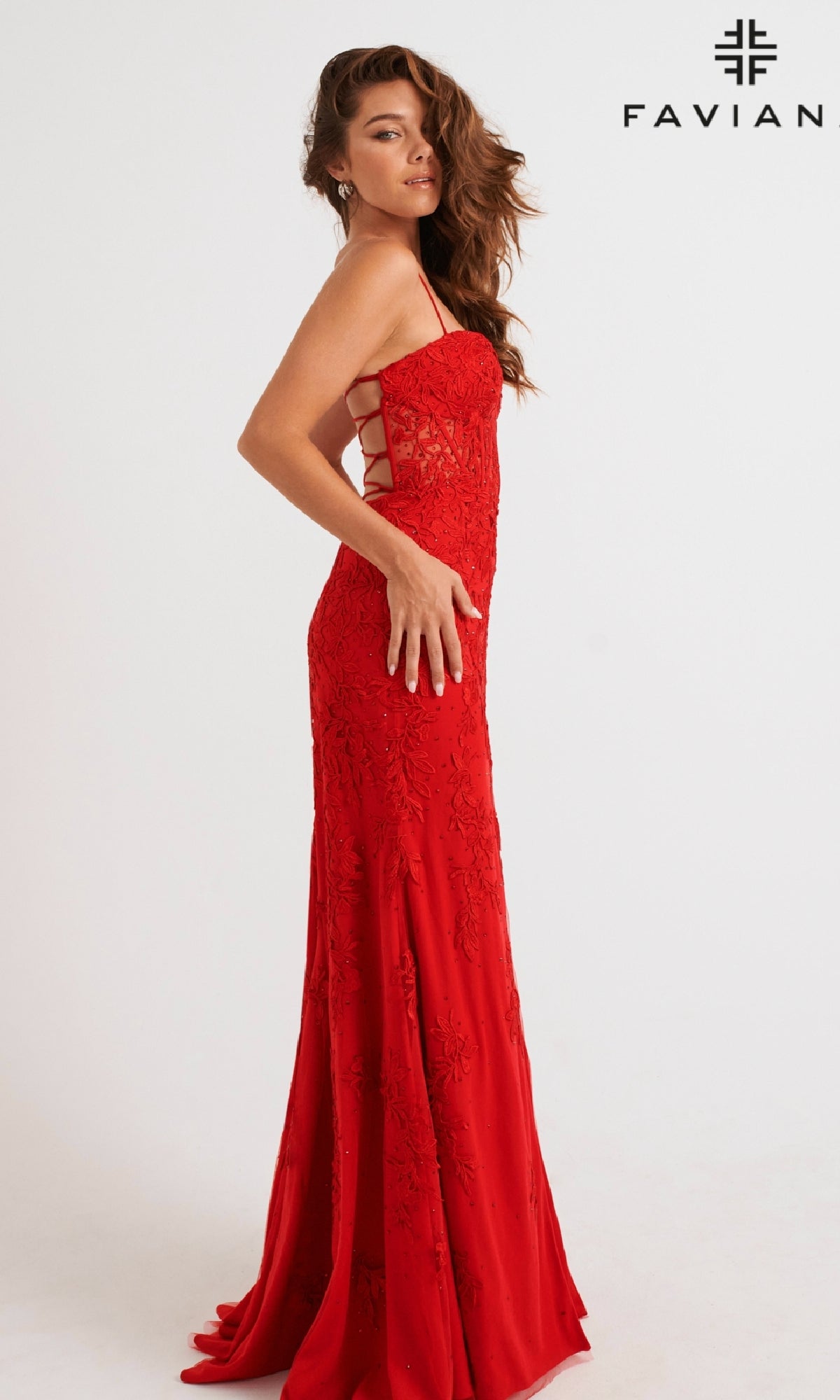 Woman in a fitted, floor-length red lace-applique gown with side cutouts, posing against a white background; FAVIAN logo in corner. This is the stunning Lace-Applique Long Faviana Prom Dress 11054—perfect for making a statement at prom.